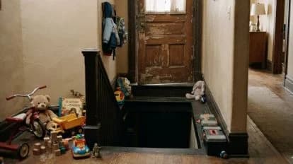 Escalera de una guardería con juguetes esparcidos y un sótano oscuro, donde se encontraron 12 niños hacinados en un automóvil.