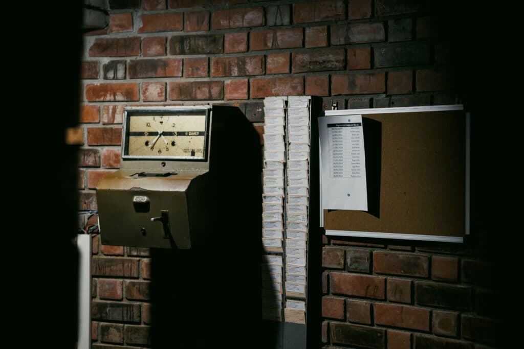 Reloj checador antiguo y tablón de anuncios en una pared de ladrillo, simbolizando el contexto laboral en México.
